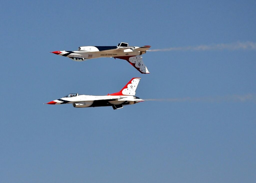Two fighter jets perform a stunning aerial maneuver at an airshow.