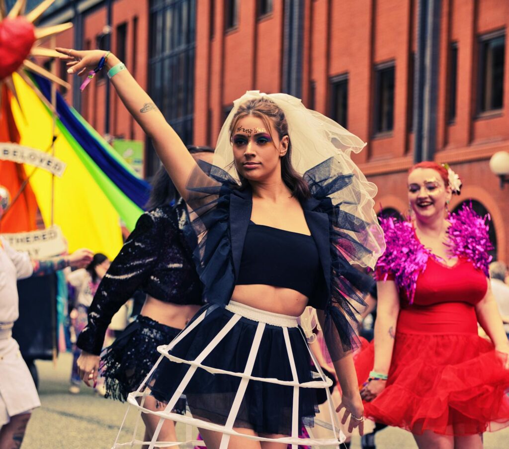 Colorful parade scene in Manchester with people in festive costumes enjoying a vibrant street celebration.