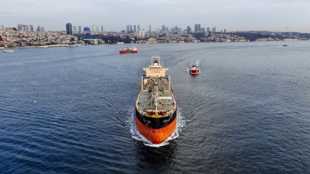 A stunning aerial shot of a cargo ship navigating the Bosphorus Strait in Istanbul, Turkey, with a city skyline.