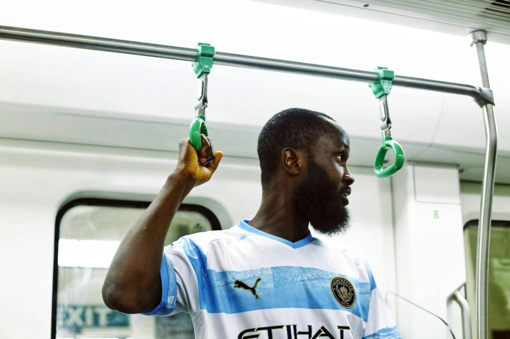 African man holding onto handrail inside a metro train, capturing urban lifestyle in Abuja.