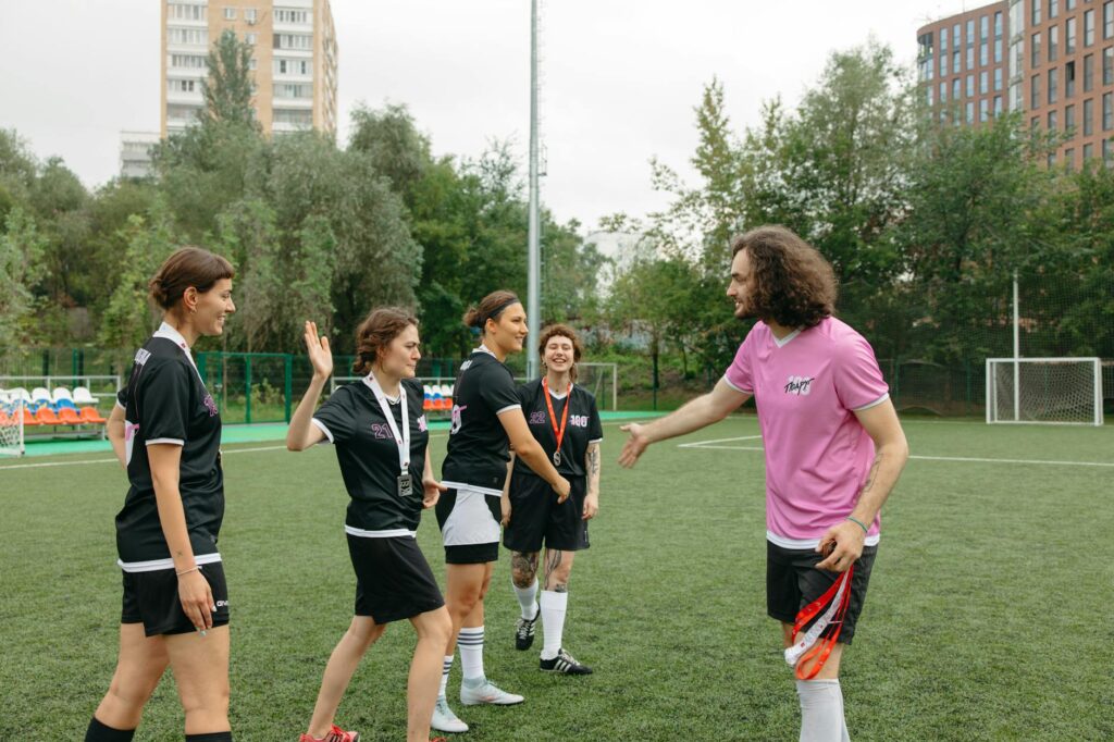 A soccer team with male and female players discussing strategies on the field.