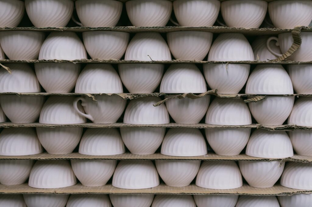 Multiple ceramic cups stacked in rows on shelves, ready for packaging or sale.