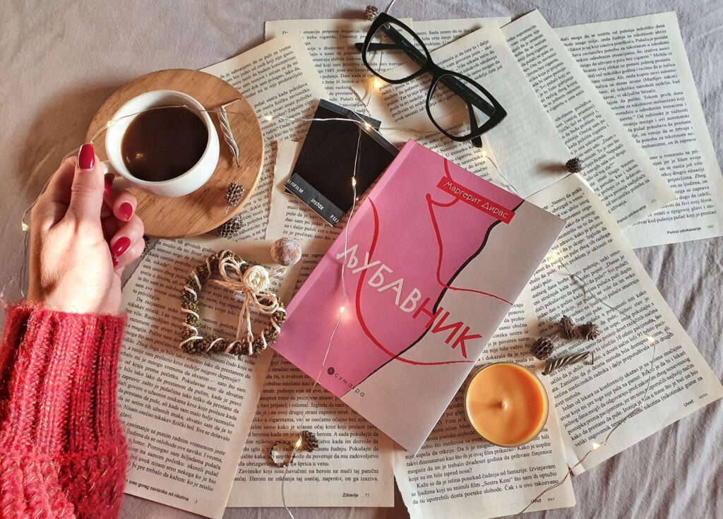 A cozy setup of coffee, book, and string lights for a relaxing reading experience.